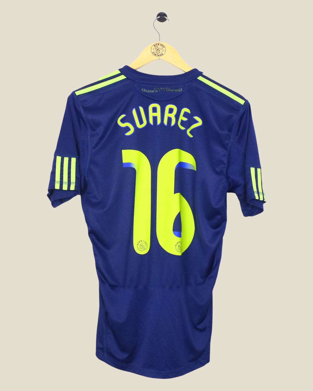 Kick Off Vintage Ajax 2010/11 away football shirt with Suarez 16 print in navy and neon yellow on a wooden hanger