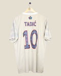 Kick Off Vintage Ajax 2022/23 third football shirt with Tadic 10 nameset on the back, beige jersey on a hanger.